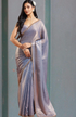 Woman wearing a light blue saree with a plain background