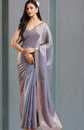 Woman wearing a light blue saree with a plain background