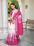 Woman wearing a pink and white saree with floral patterns indoors.