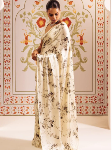 Woman in a floral dress standing in front of a decorated wall with floral patterns.