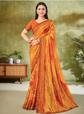 Woman wearing a bright orange and red saree with a blurred indoor background