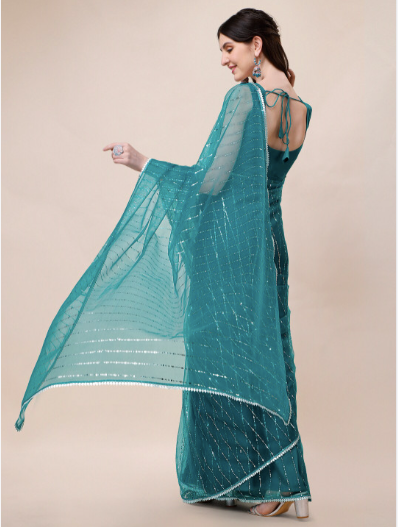Woman wearing a teal saree with a matching blouse on a beige background