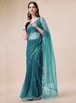Woman wearing a teal saree with a beige background