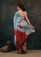 Woman wearing a red and blue floral dress against a dark textured wall.