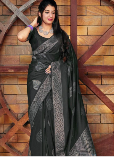 Woman wearing a black saree with a patterned border against a wooden background
