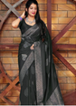 Woman wearing a black saree with a patterned border against a wooden background