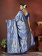 Woman wearing a blue saree with a matching blouse against a red background
