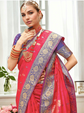 Woman wearing a traditional pink and purple saree with jewelry indoors.