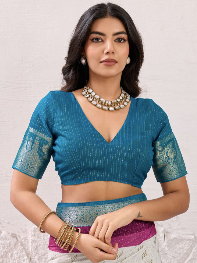 Woman wearing a blue blouse with intricate designs on a light background