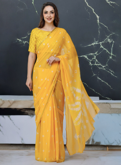 Woman wearing a yellow saree with a white pattern against a marble background